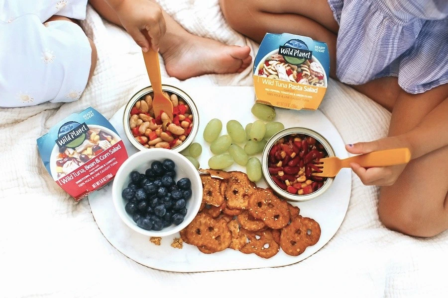two kids hands holding fork in front of tuna salad in bowls